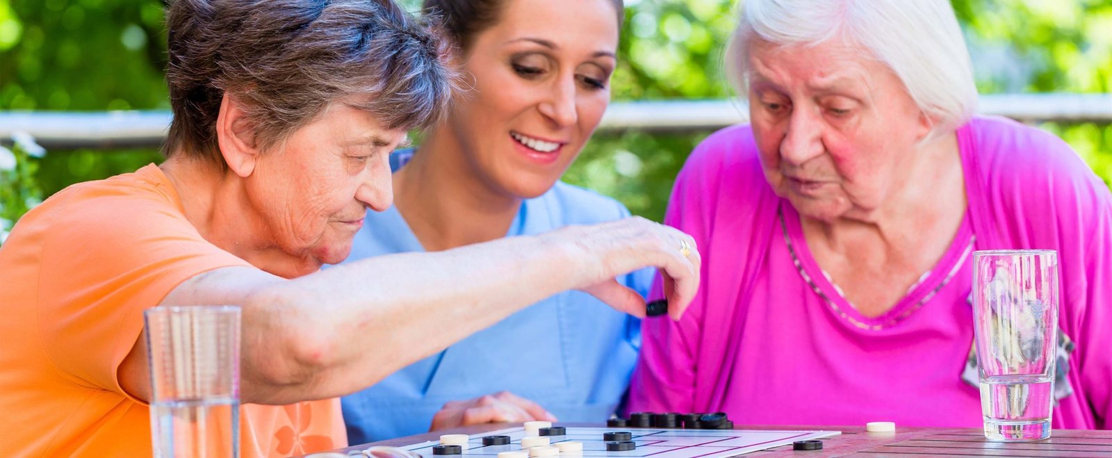 Two senior ladies playing board game in rest home