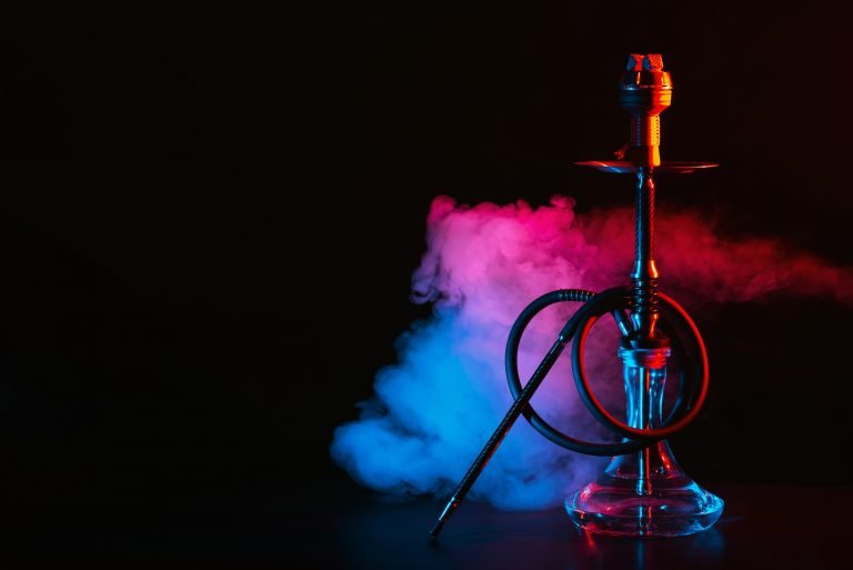 hookah with a glass flask and a metal bowl shisha with colored smoke on the table