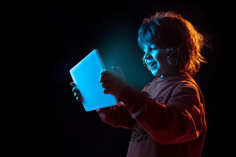 Caucasian boy's portrait isolated on dark studio background in neon light