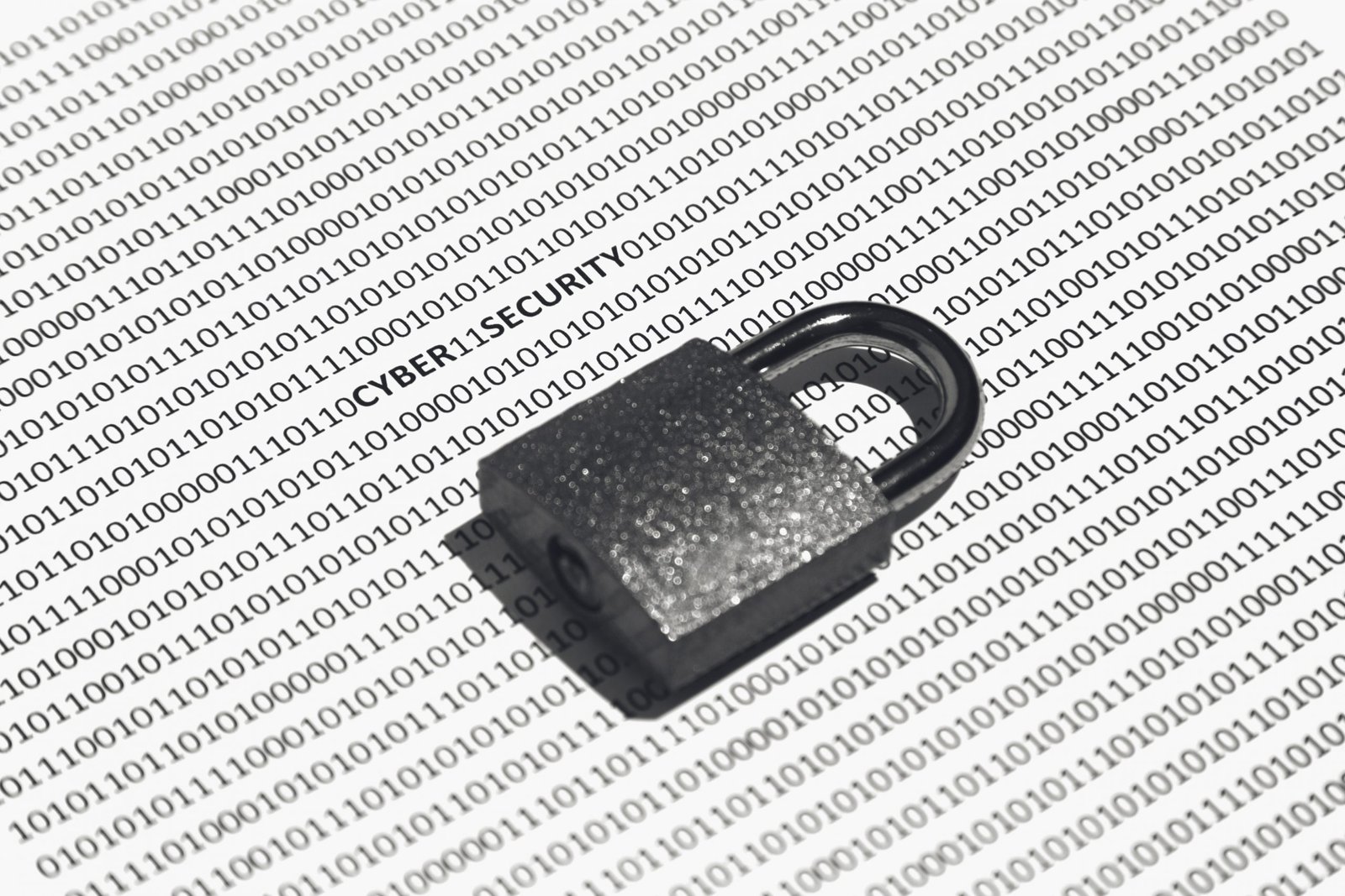 Closeup shot of a lock on a white surface with cyber security, ones, and zeros written on it