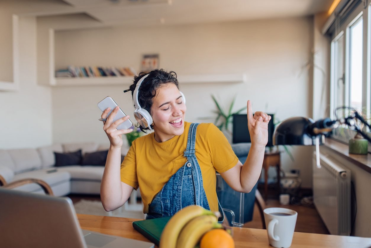 Excited young woman dancing and listening to the music after work