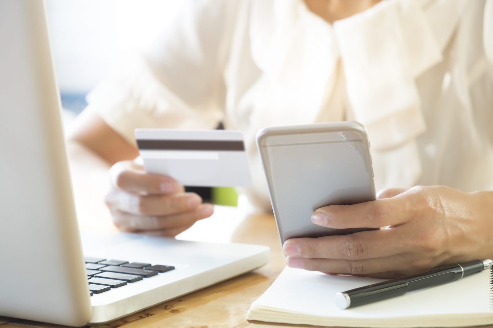 Woman holding mobile phone and credit card on laptop for online