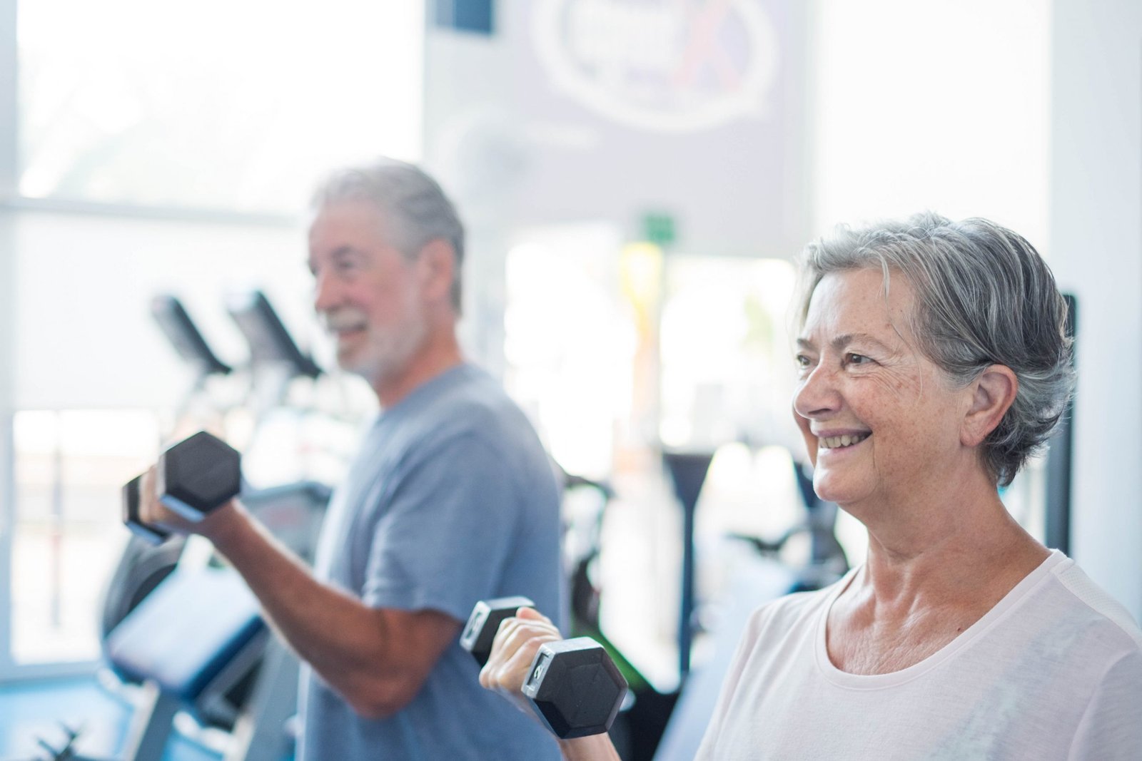 couple of two seniors training together at the gym with dumbbell