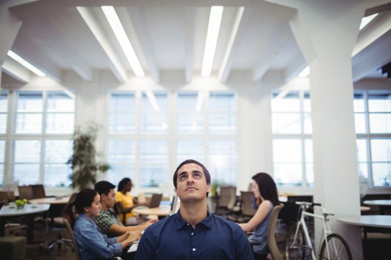 Man looking up while colleagues working in background