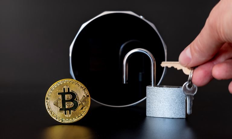 A Bitcoin and a lock in front of a Cryptocurrency Hardware Wallet .