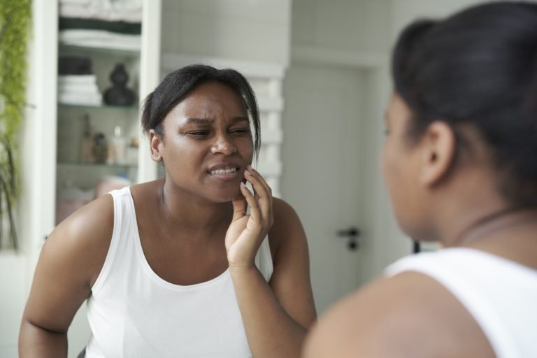 African-American woman  in the bathroom having a strong toothache or bruxism
