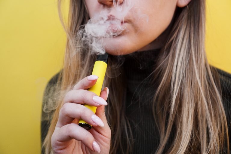 A,Young,Girl,Smokes,Disposable,Electronic,Cigarette.,Bright,Yellow,Background