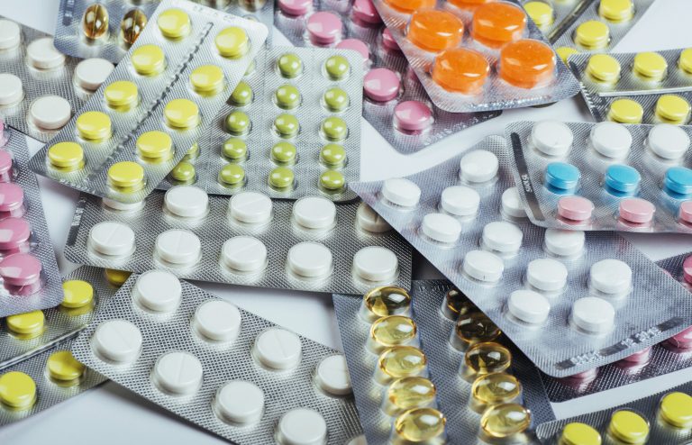 Pills of different colors lie on the surface in a sealed package.