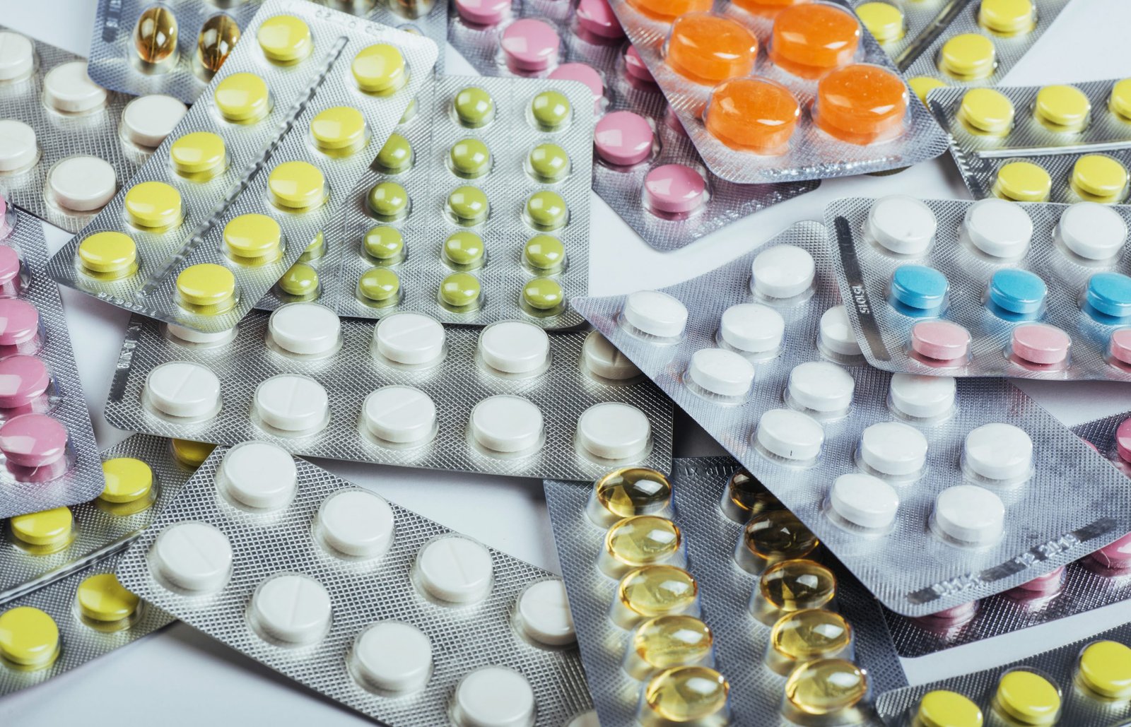 Pills of different colors lie on the surface in a sealed package.