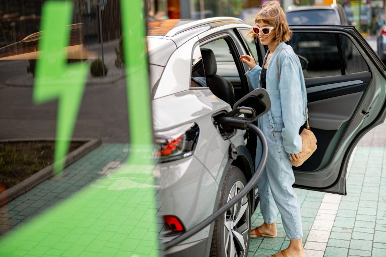 Woman charging electric car while shopping