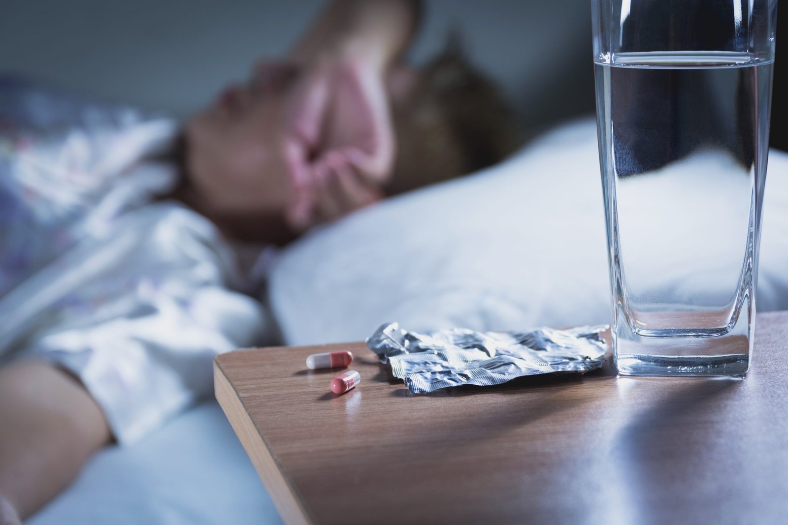 Sick woman takes capsule pill and drink water before sleeping fo