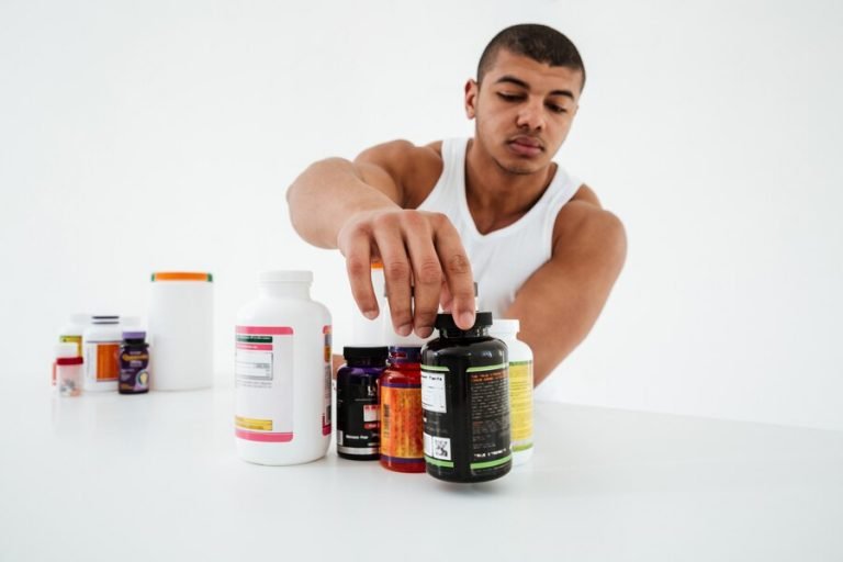 sportsman-standing-white-wall-holding-vitamins_171337-15334