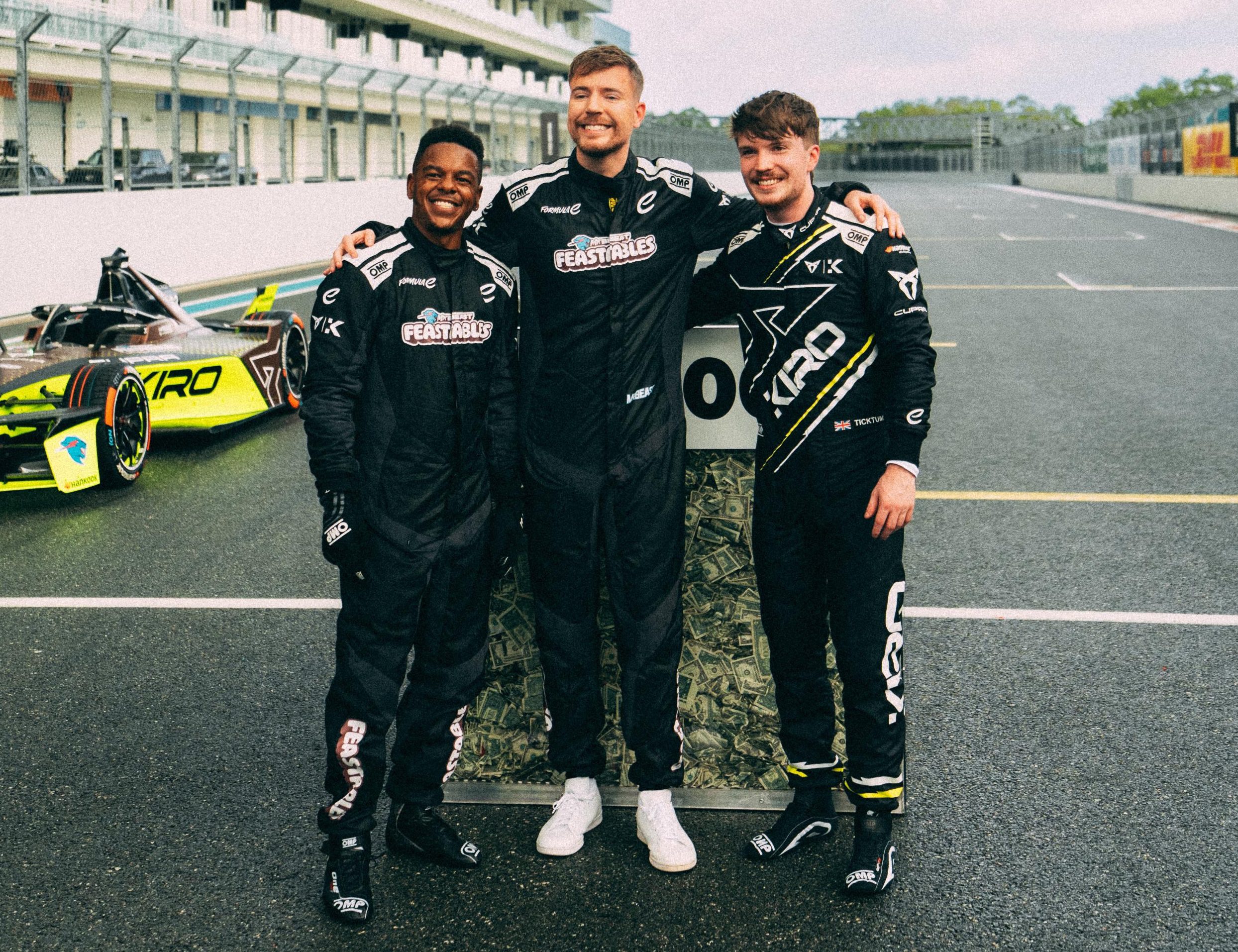 Cupra Kiro/Divulgação Da direita para a esquerda, Dan Ticktum, MrBeast e seu amigo Ronnie se abraçam na pista, ao lado do GEN3 Evo da Cupra Kiro