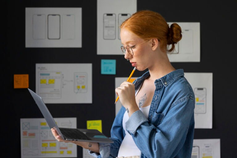 Web designer feminina no escritório com laptop freepik